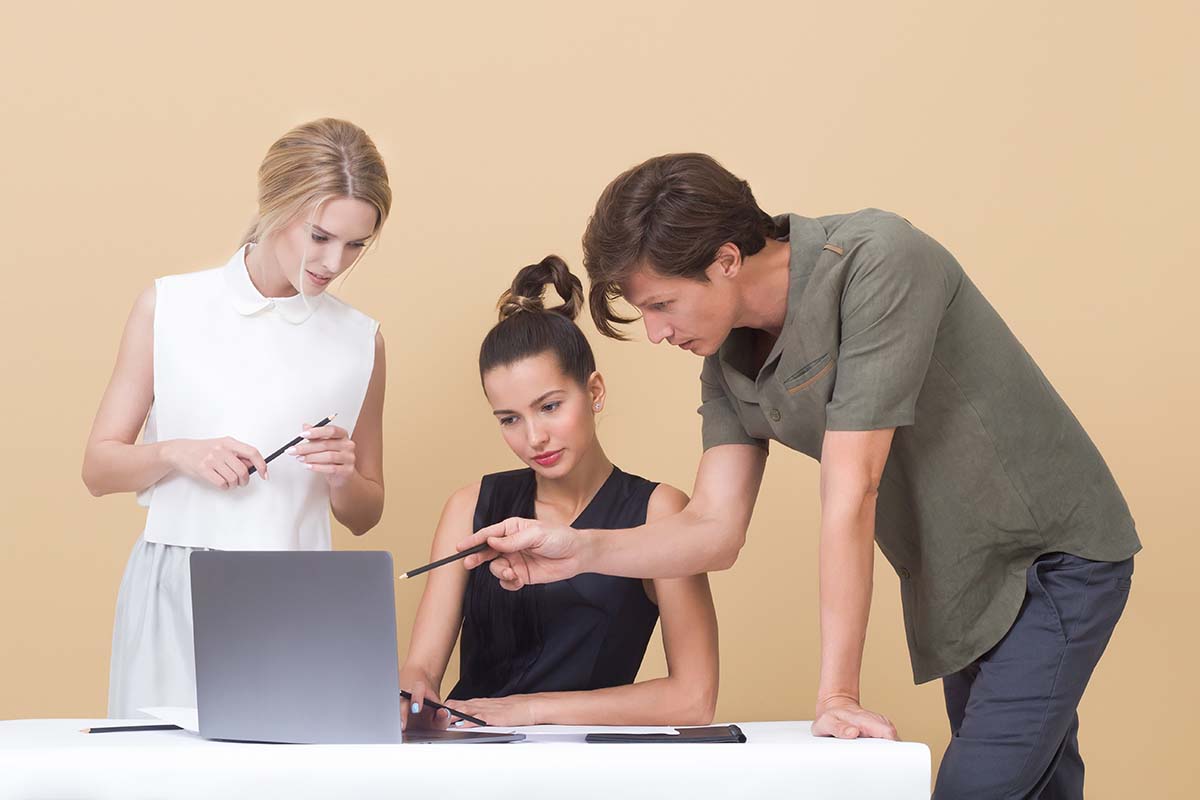 Three colleagues looking at a laptop