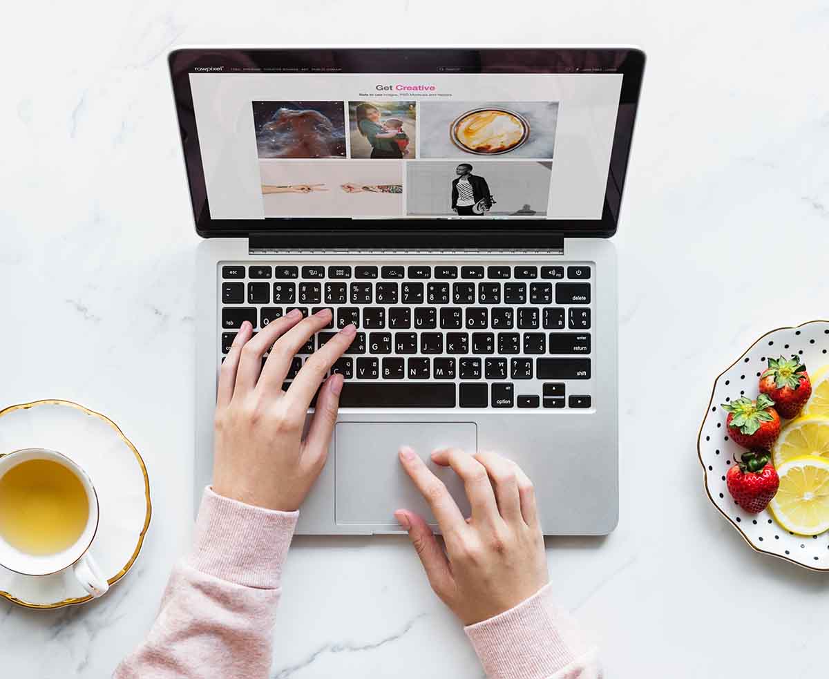 Woman looking at a blog with a cup of tea next to her