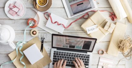 A person working on a laptop surrounded by wedding paraphernalia