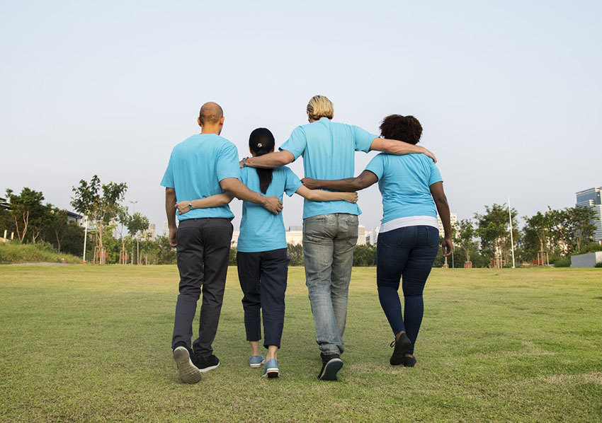 4 people walking along in matching shirts