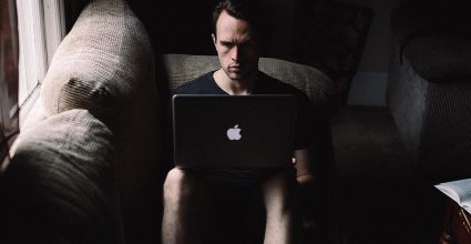 A person working on a laptop in a dark room